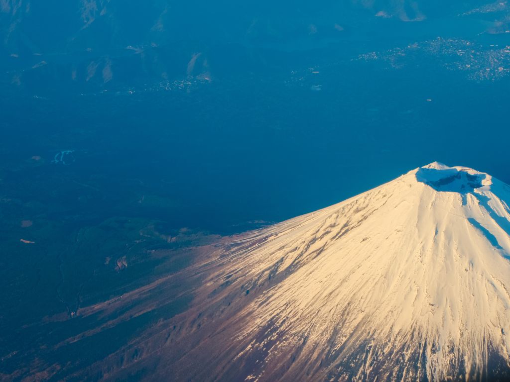 Aerial photograph of Mount Fuji showing its snow‑covered crater and surrounding volcanic slopes.