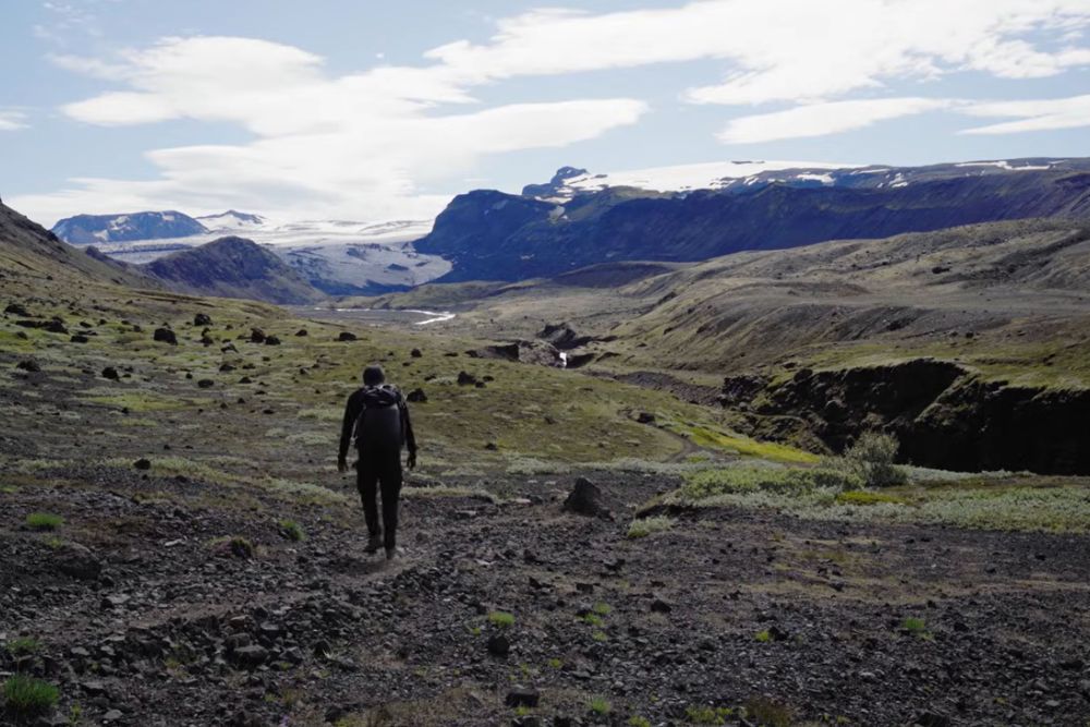 hiker crossing a glacial valley in the icelandic highlands