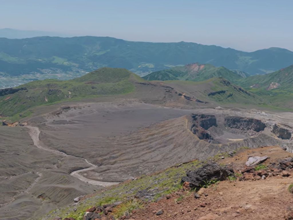 Aerial view of the Aso caldera at sunrise, showing the central peaks and the inhabited floor stretching to the far rim.