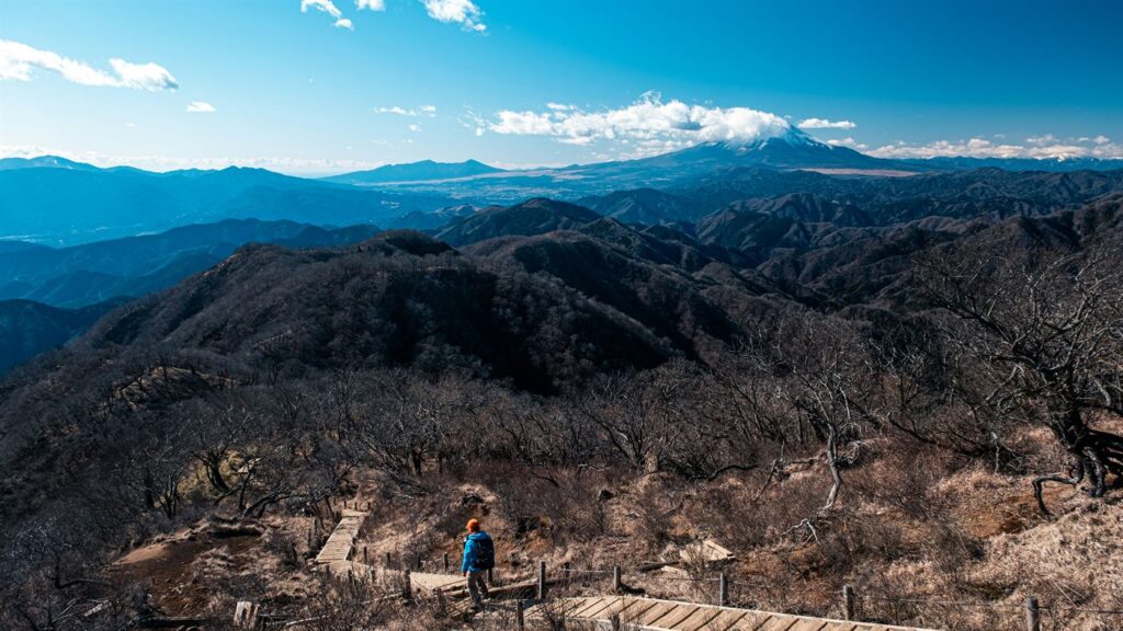 Small group walking on a dirt road through Japanese countryside with mountains in the background
