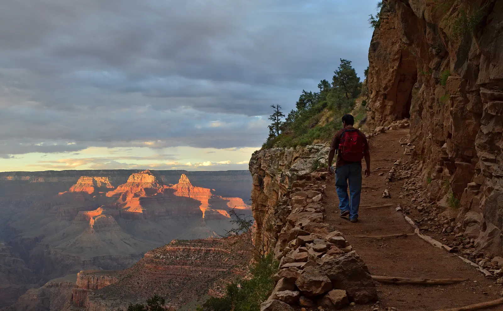 Hiker with red backpack on a Grand Canyon trail edge