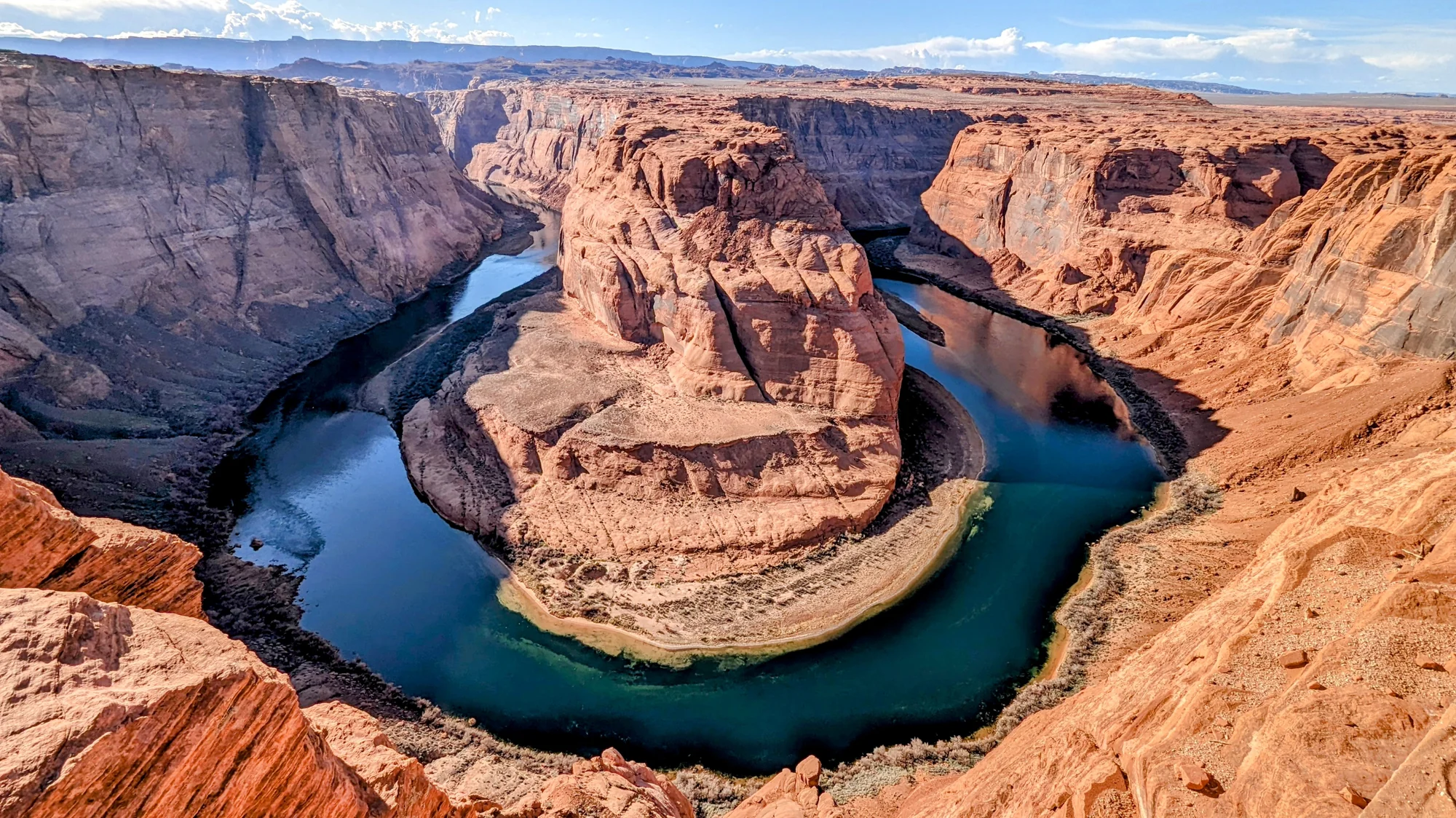Horseshoe Bend at sunset, with the sandstone walls lit orange and the Colorado River reflecting the sky.