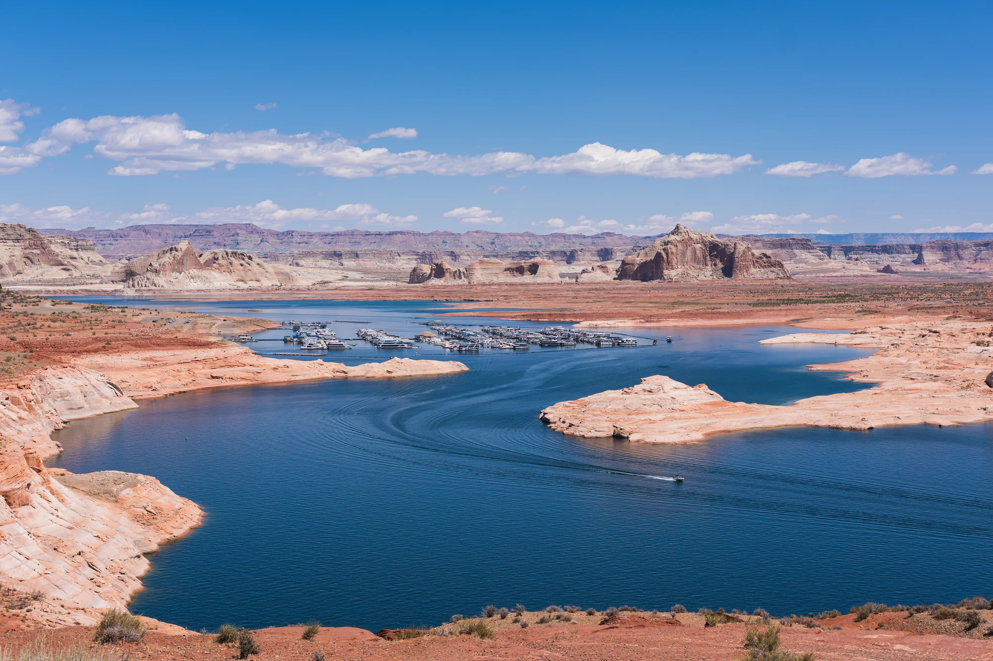 Aerial view of Page Arizona with Lake Powell in the background, Glen Canyon Dam, and the Colorado River cutting through the sandstone plateau.